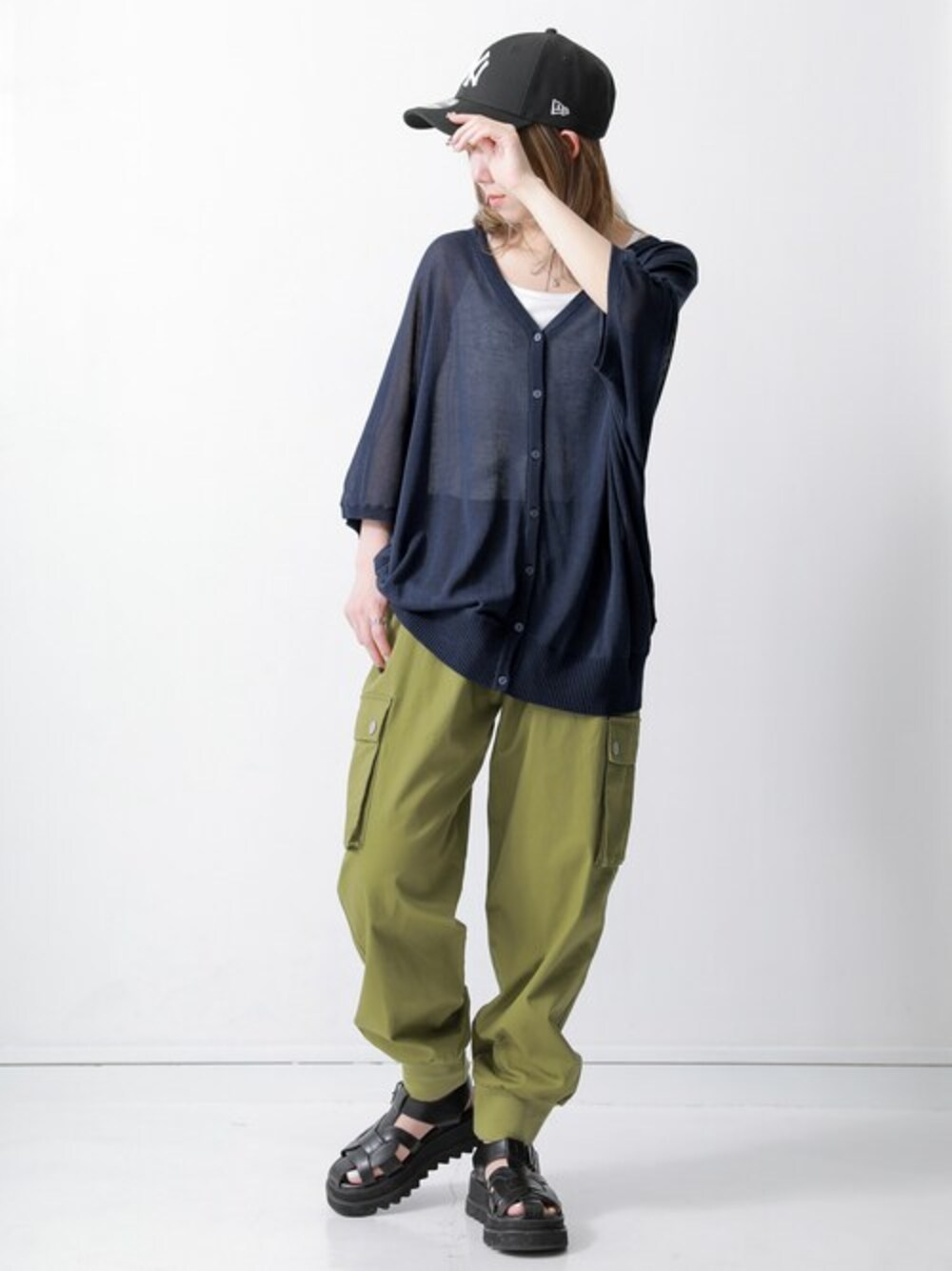 グリーン系のカーゴパンツ、ブルー系のカーディガン/ボレロ、ホワイト系のインナーウェア/肌着を着用したレディースの春コーディネートの1枚目の写真