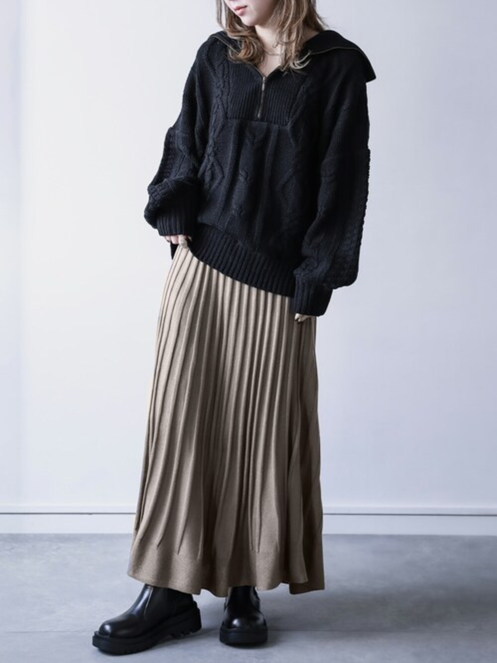 グレー系のスカート、ブラック系のニット/セーターを着用したレディースの秋コーディネートの1枚目の写真