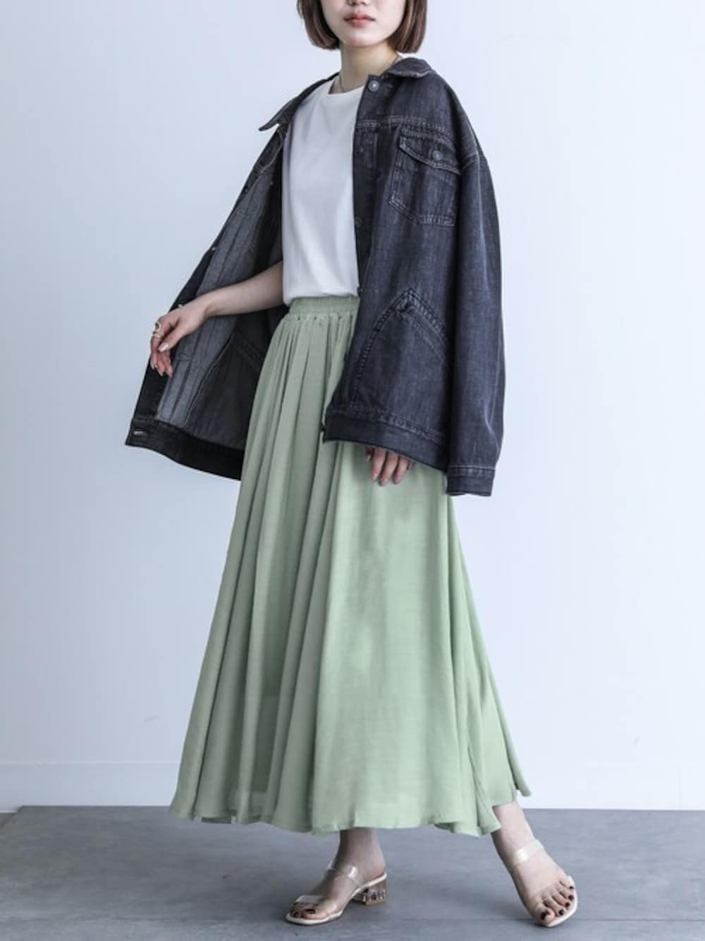 グリーン系のスカートを着用したレディースの春コーディネートの1枚目の写真