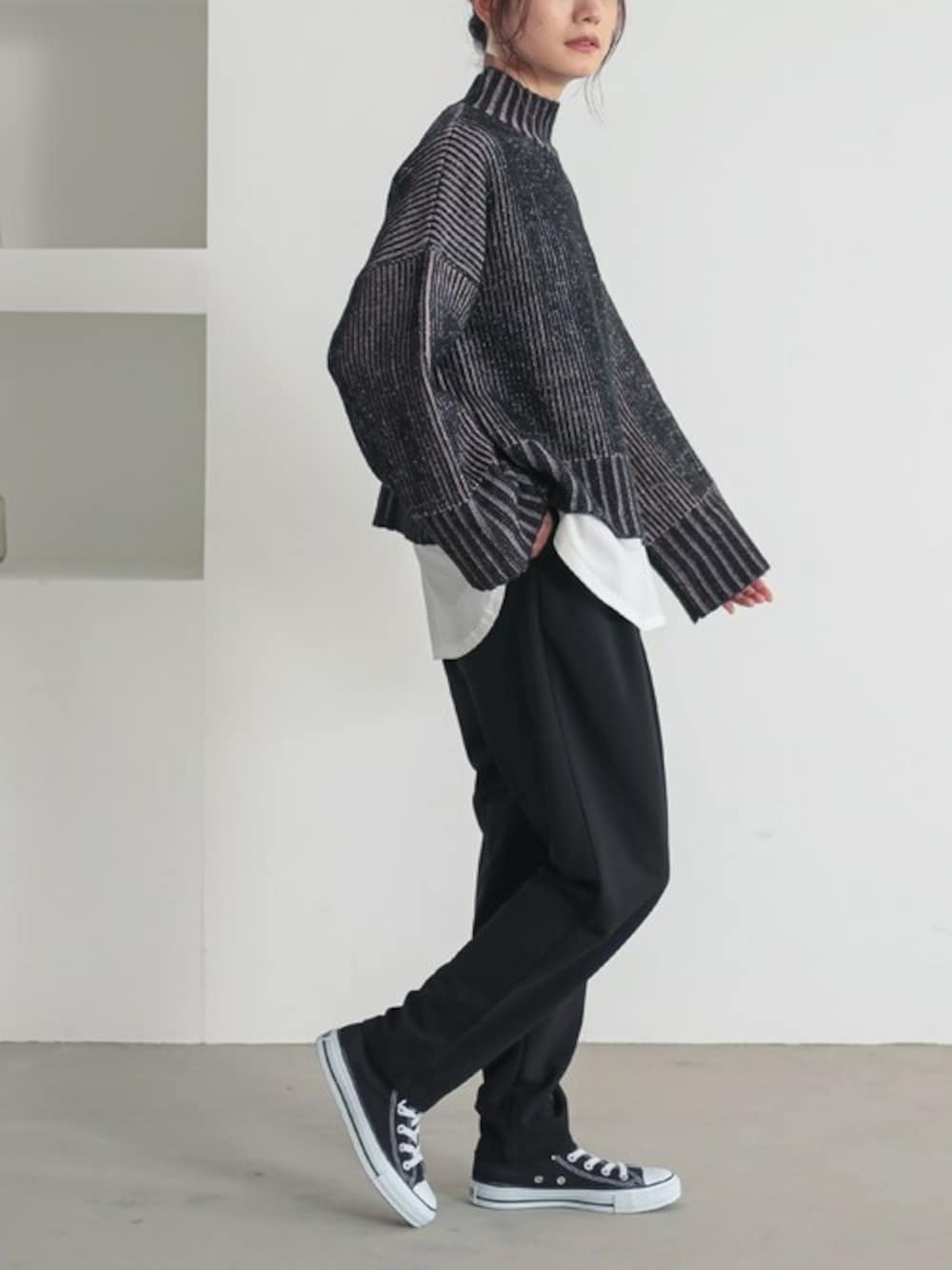 ブラック系のニット/セーター、ホワイト系のTシャツ/カットソー、ブラック系のスラックスを着用したレディースの冬コーディネートの1枚目の写真