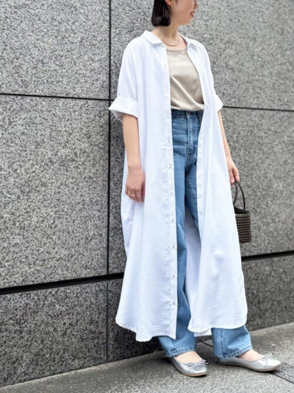 ホワイト系のシャツワンピース、ブルー系のデニムパンツ、ベージュ系のタンクトップを着用したレディースの春コーディネートの1枚目の写真