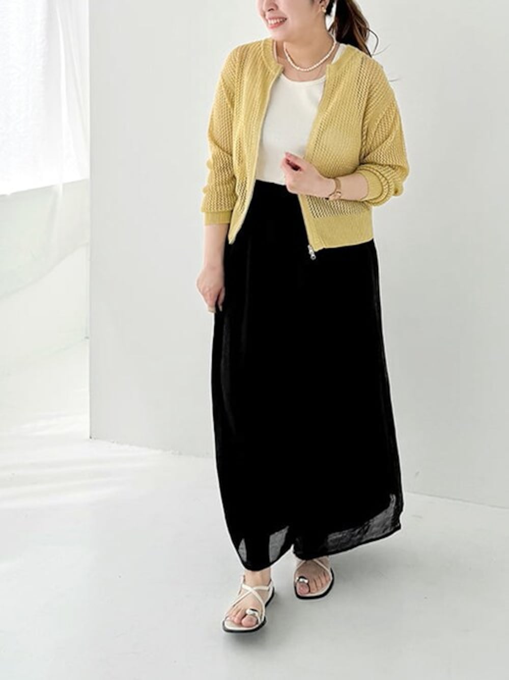 ブラック系のその他パンツ、イエロー系のカーディガン/ボレロ、ホワイト系のタンクトップを着用したレディースの春コーディネートの1枚目の写真