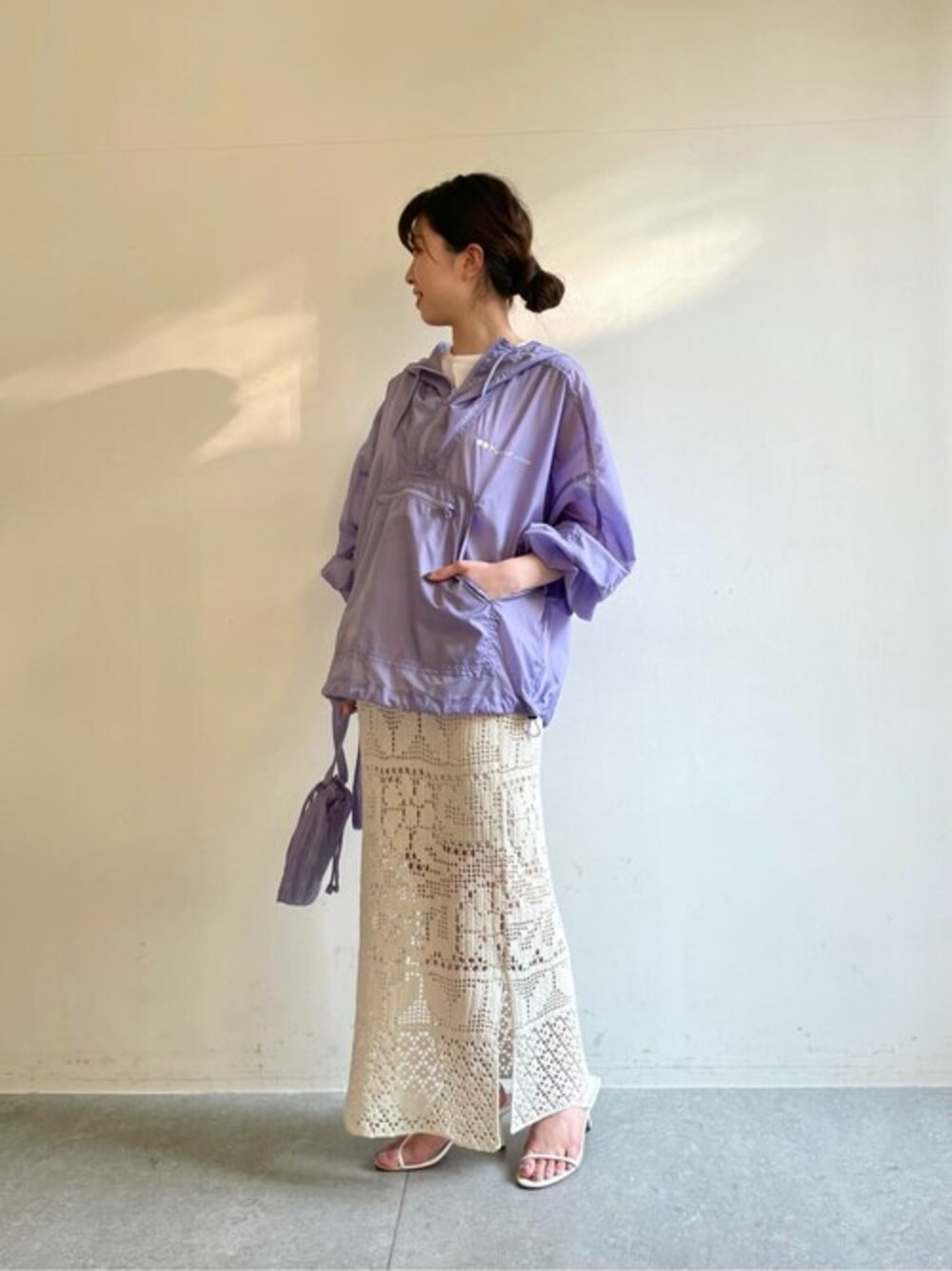 パープル系のナイロンジャケット、ホワイト系のスカート、パープル系のショルダーバッグを着用したレディースの冬コーディネートの1枚目の写真