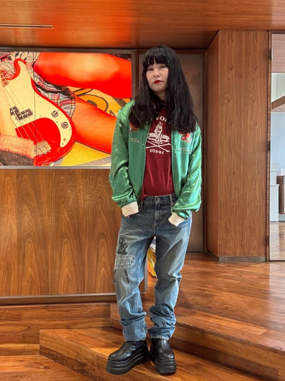 レッド系のTシャツ/カットソー、グリーン系のブルゾン、ブルー系のデニムパンツを着用したレディースの秋コーディネートの1枚目の写真