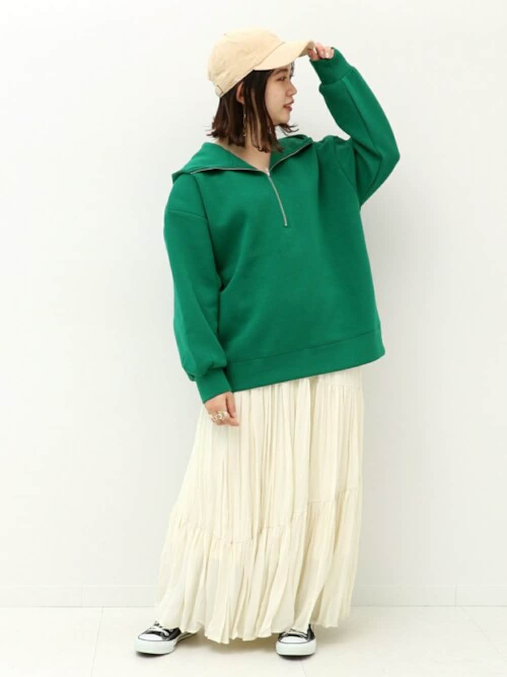 グリーン系のパーカー、ベージュ系のスカート、ホワイト系のハットを着用したレディースの冬コーディネートの1枚目の写真