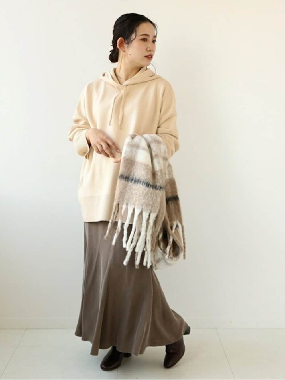 ホワイト系のニット/セーター、ブラウン系のスカートを着用したレディースの冬コーディネートの1枚目の写真