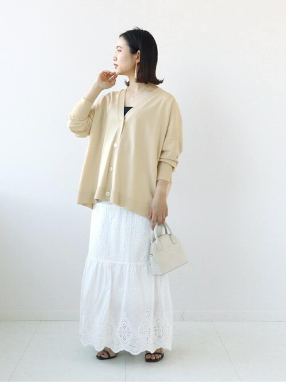 ホワイト系のカーディガン/ボレロ、ホワイト系のショルダーバッグ、ホワイト系のスカートを着用したレディースの春コーディネートの1枚目の写真