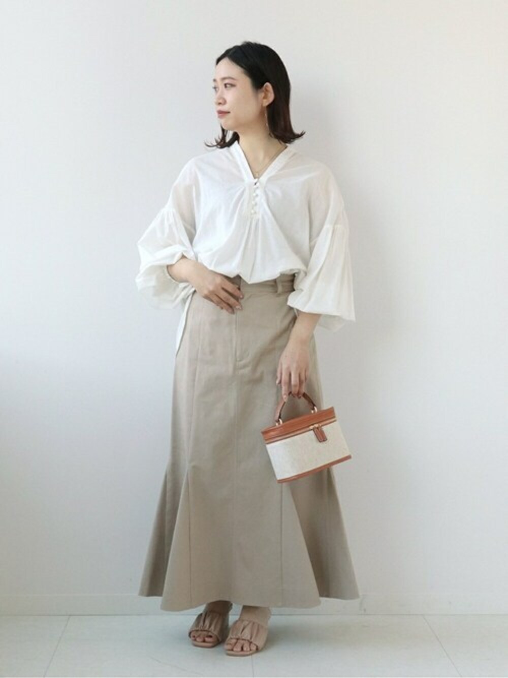 ホワイト系のシャツ/ブラウス、ベージュ系のスカート、ブラウン系のショルダーバッグを着用したレディースの春コーディネートの1枚目の写真