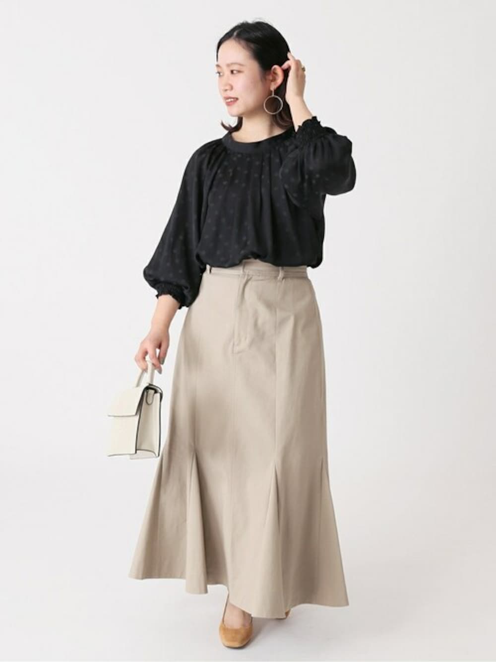 ベージュ系のスカート、ブラック系のシャツ/ブラウス、ホワイト系のショルダーバッグを着用したレディースの春コーディネートの1枚目の写真