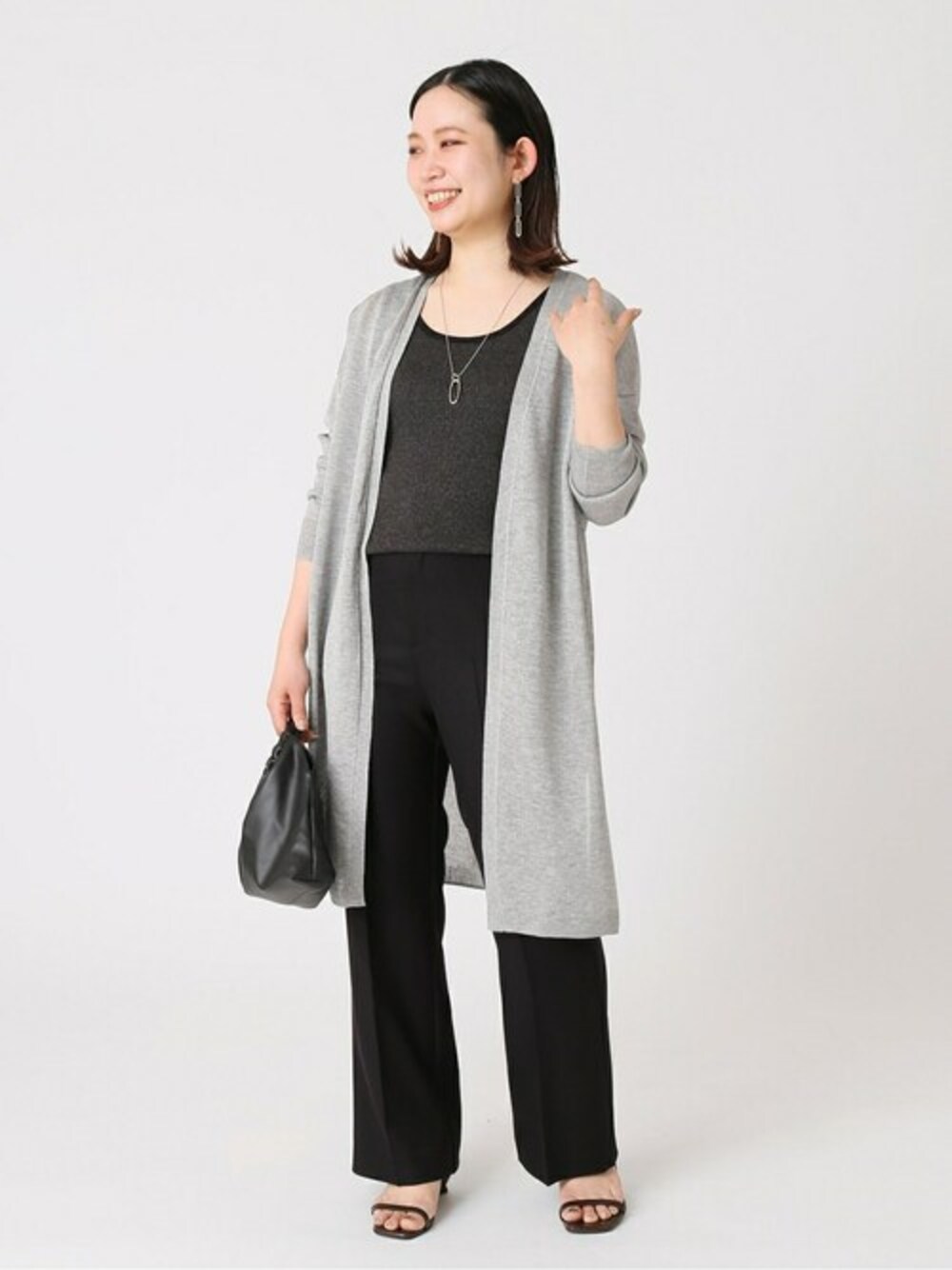 グレー系のカーディガン/ボレロ、グレー系のタンクトップ、ブラック系のスラックスを着用したレディースの春コーディネートの1枚目の写真