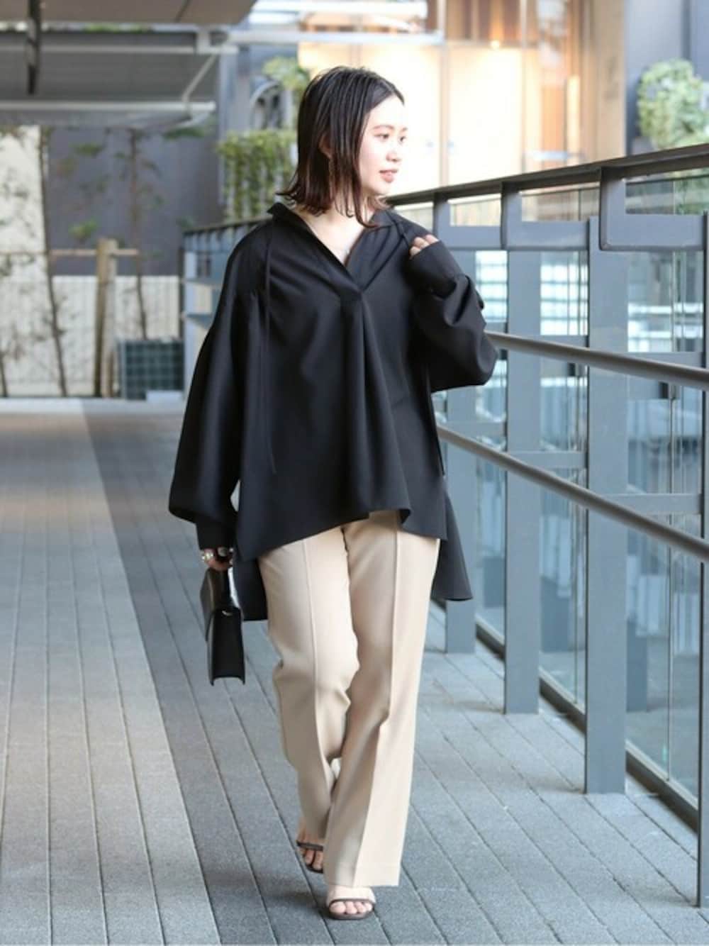 ブラック系のシャツ/ブラウス、ベージュ系のスラックス、ブラック系のショルダーバッグを着用したレディースの春コーディネートの1枚目の写真