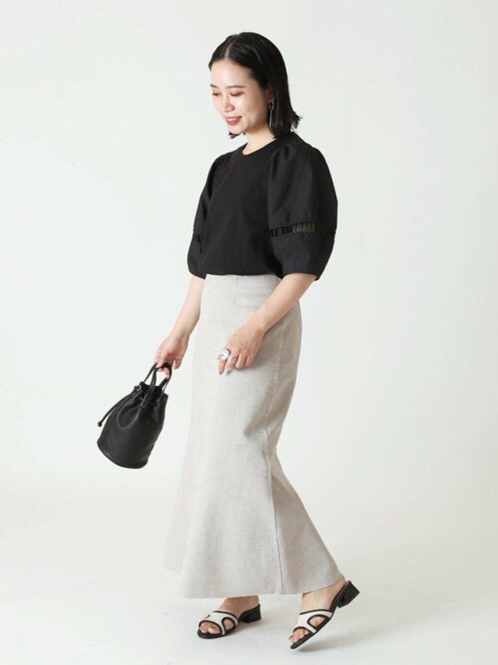 ブラック系のTシャツ/カットソー、ホワイト系のスカート、ブラック系のサンダルを着用したレディースの夏コーディネートの1枚目の写真