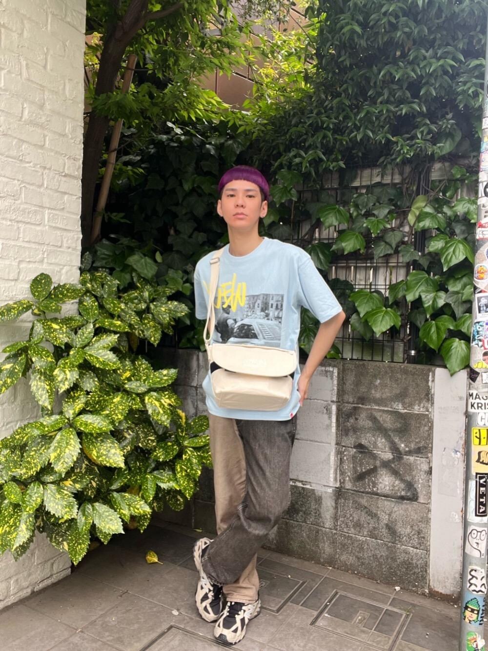 ベージュ系のメッセンジャーバッグ、ブルー系のTシャツ/カットソーを着用したメンズの春コーディネートの1枚目の写真