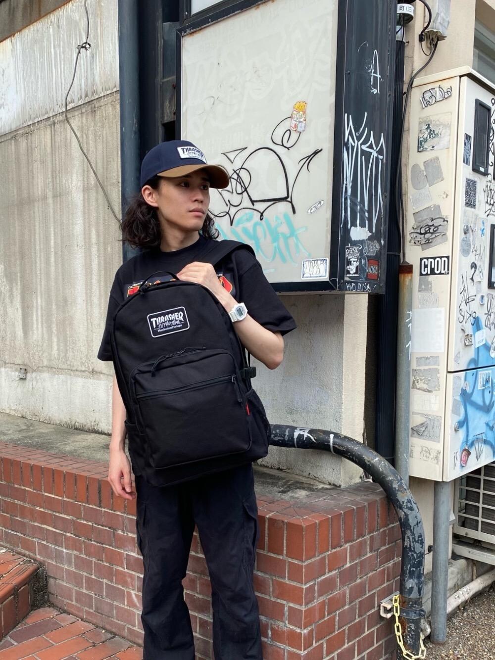 ブラック系のバックパック/リュック、ブラック系のTシャツ/カットソー、ブルー系のキャップを着用したメンズの夏コーディネートの1枚目の写真