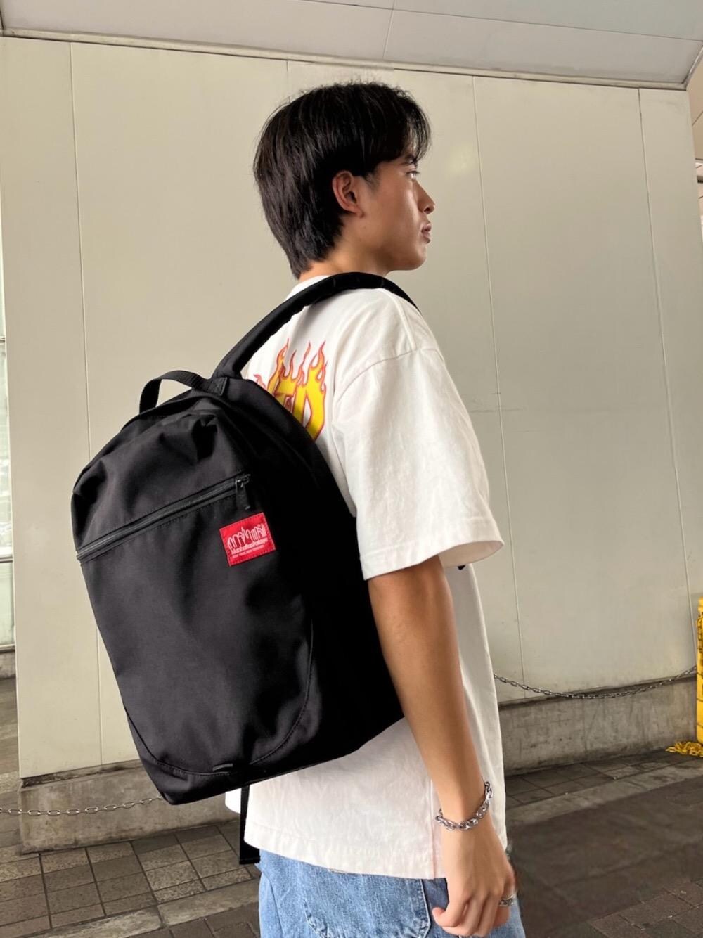 ブラック系のバックパック/リュック、ホワイト系のTシャツ/カットソーを着用したメンズの夏コーディネートの1枚目の写真