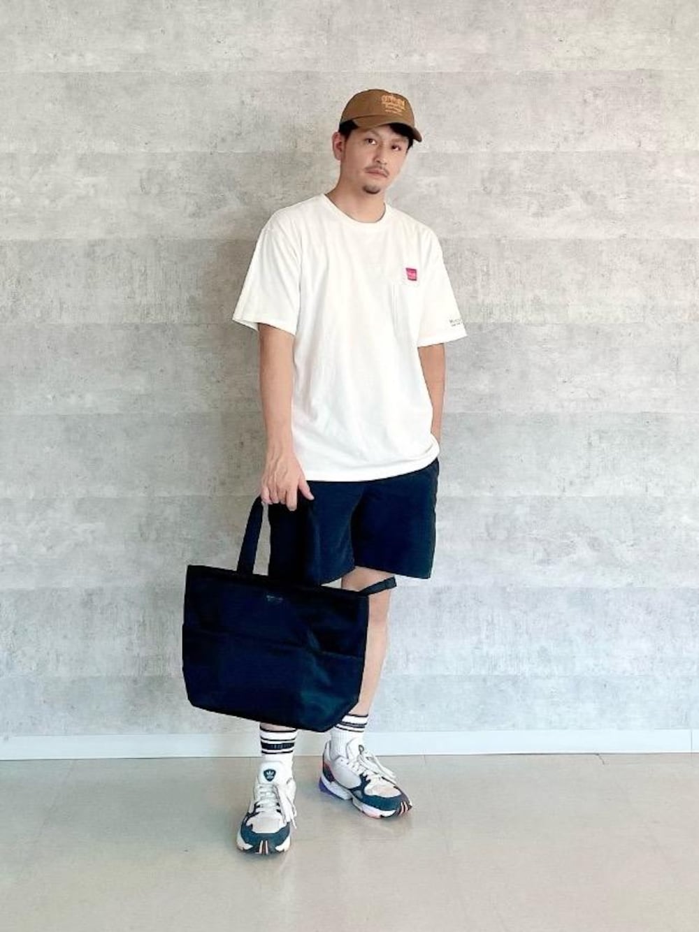 ブラック系のトートバッグ、ホワイト系のTシャツ/カットソーを着用したメンズの夏コーディネートの1枚目の写真