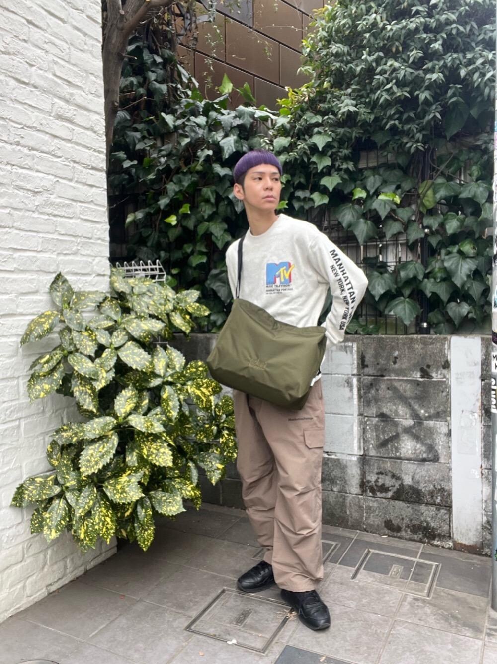 グリーン系のショルダーバッグ、ベージュ系のTシャツ/カットソーを着用したメンズの春コーディネートの1枚目の写真