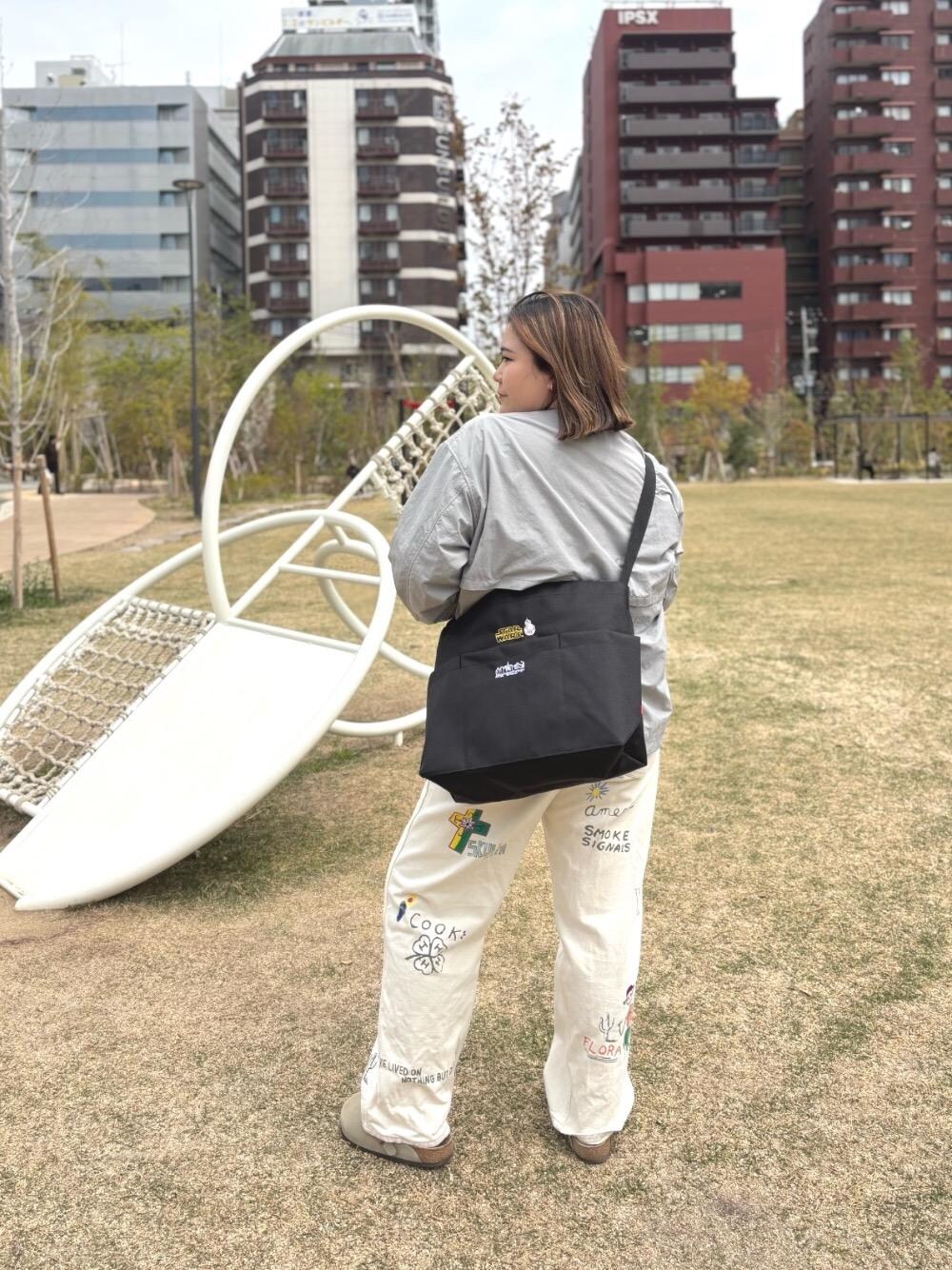 グレー系のナイロンジャケット、ブラック系のショルダーバッグを着用したレディースの春コーディネートの1枚目の写真