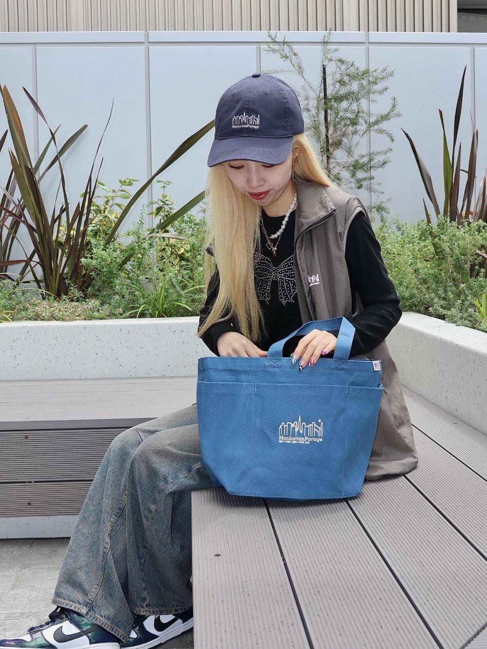 ベージュ系のその他アウター、ブルー系のトートバッグ、グレー系のキャップを着用したレディースの春コーディネートの1枚目の写真