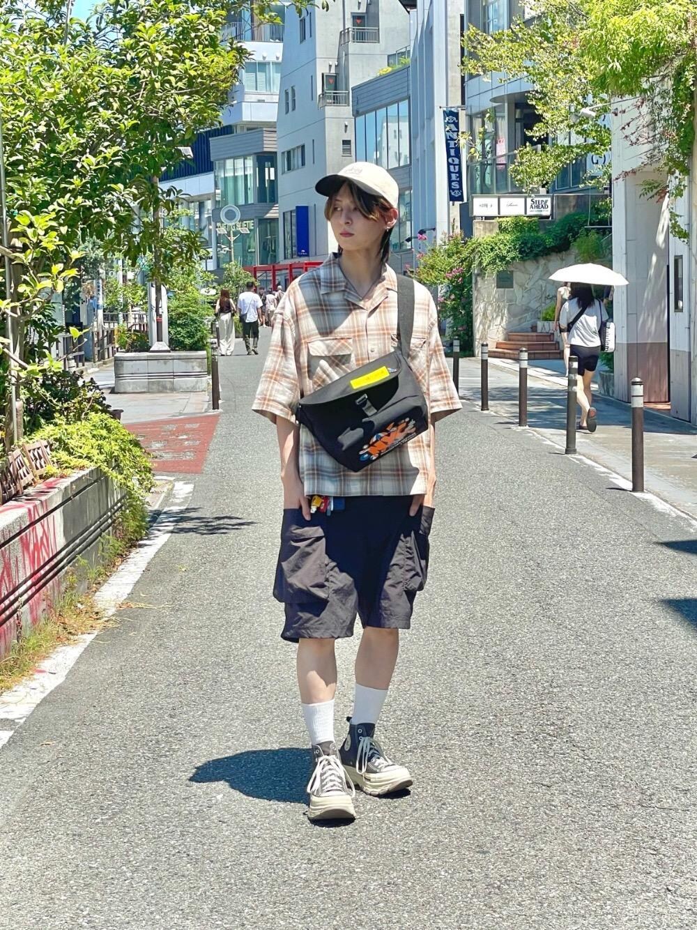 ブラック系のメッセンジャーバッグ、ホワイト系のキャップを着用したメンズの夏コーディネートの1枚目の写真