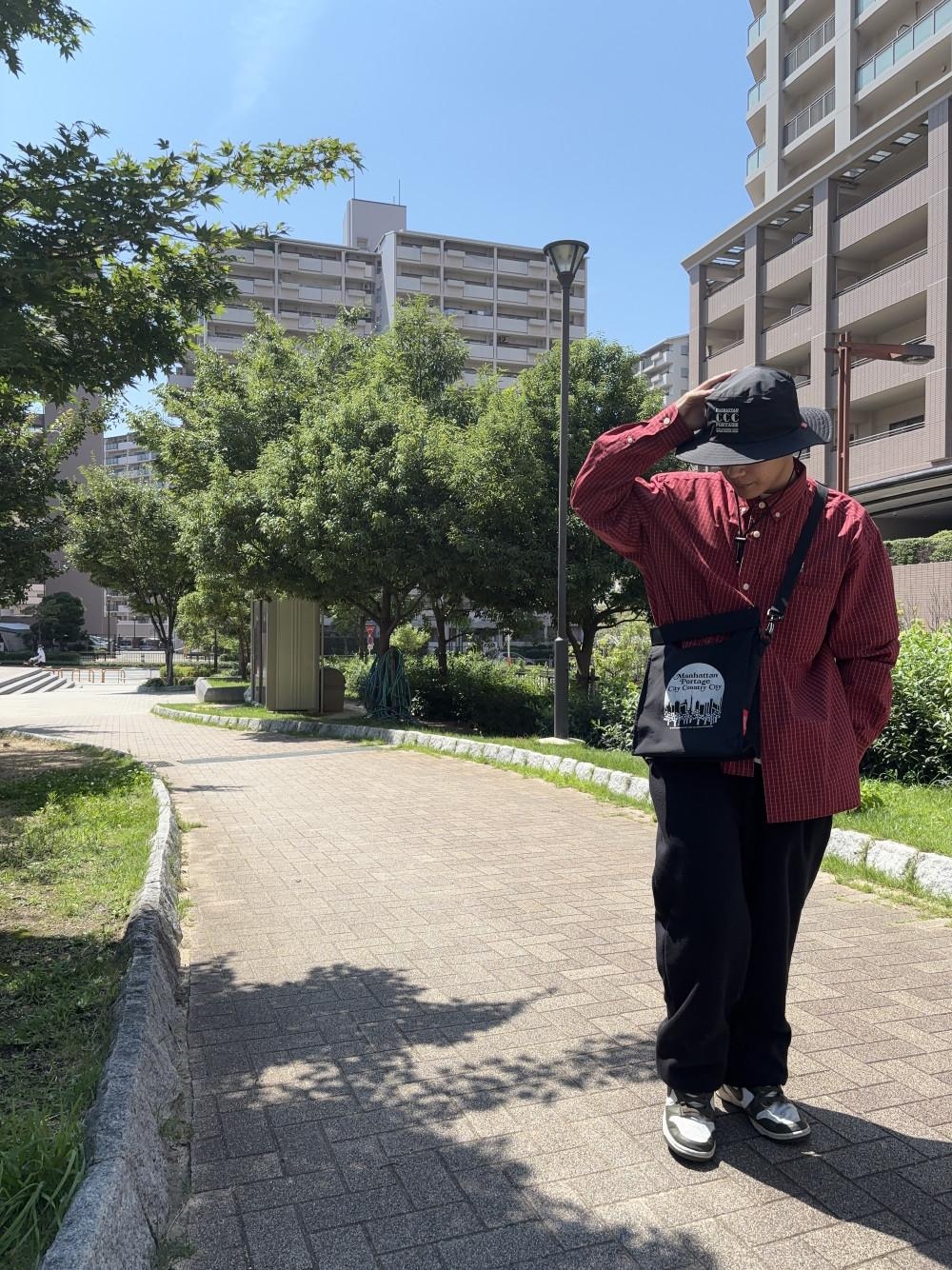 ブラック系のショルダーバッグ、ブラック系のハットを着用したメンズの夏コーディネートの1枚目の写真