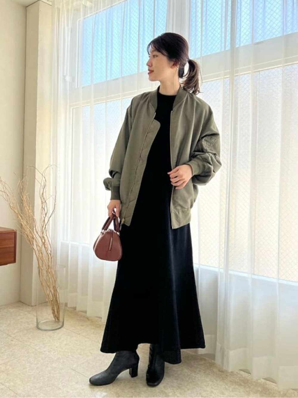 グリーン系のMA-1、イエロー系のハンドバッグ、ブラック系のワンピースを着用したレディースの秋コーディネートの1枚目の写真