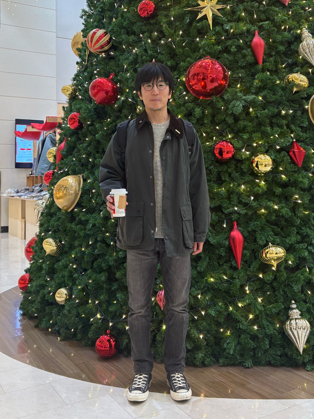 グリーン系のミリタリージャケット、グレー系のニット/セーター、ブラック系のデニムパンツを着用したメンズの冬コーディネートの1枚目の写真