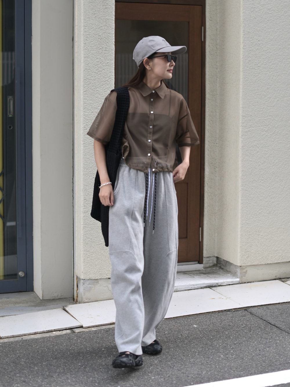 グレー系のスウェットパンツ、ブラック系のトートバッグ、グレー系のキャップを着用したレディースの夏コーディネートの1枚目の写真