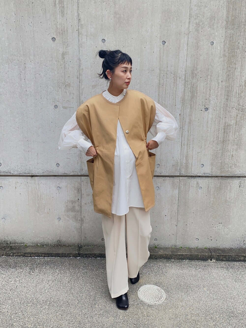 ホワイト系のシャツ/ブラウス、ブラック系のブーツ、ベージュ系のベストを着用したレディースの秋コーディネートの1枚目の写真