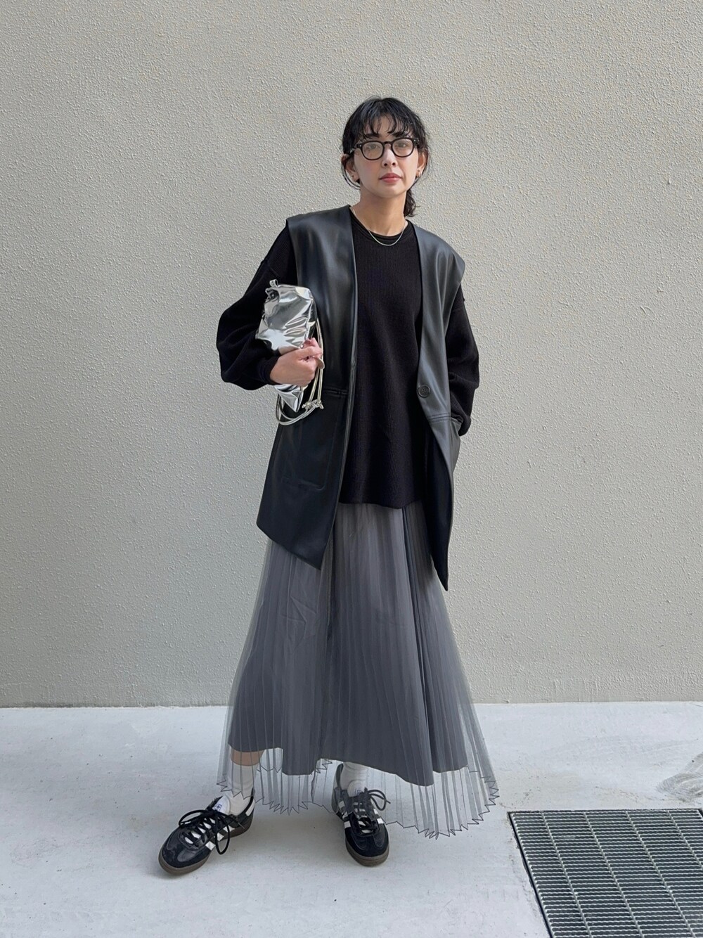 ブラック系のスカート、シルバー系のショルダーバッグ、ブラック系のスニーカーを着用したレディースの春コーディネートの1枚目の写真