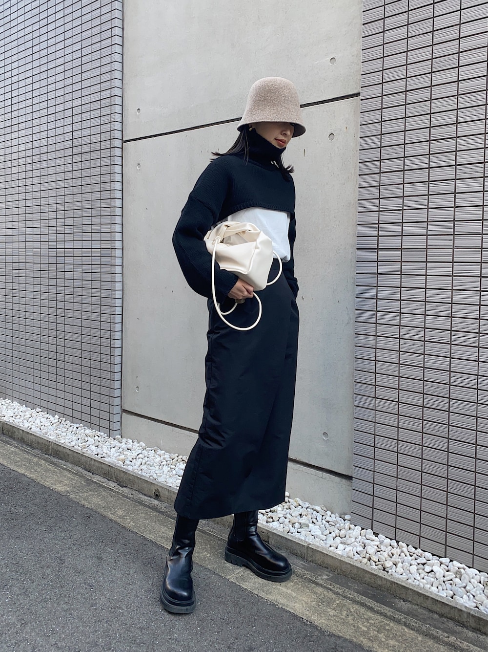 ブラック系のニット/セーター、ブラック系のスカート、ホワイト系のTシャツ/カットソーを着用したレディースの冬コーディネートの1枚目の写真