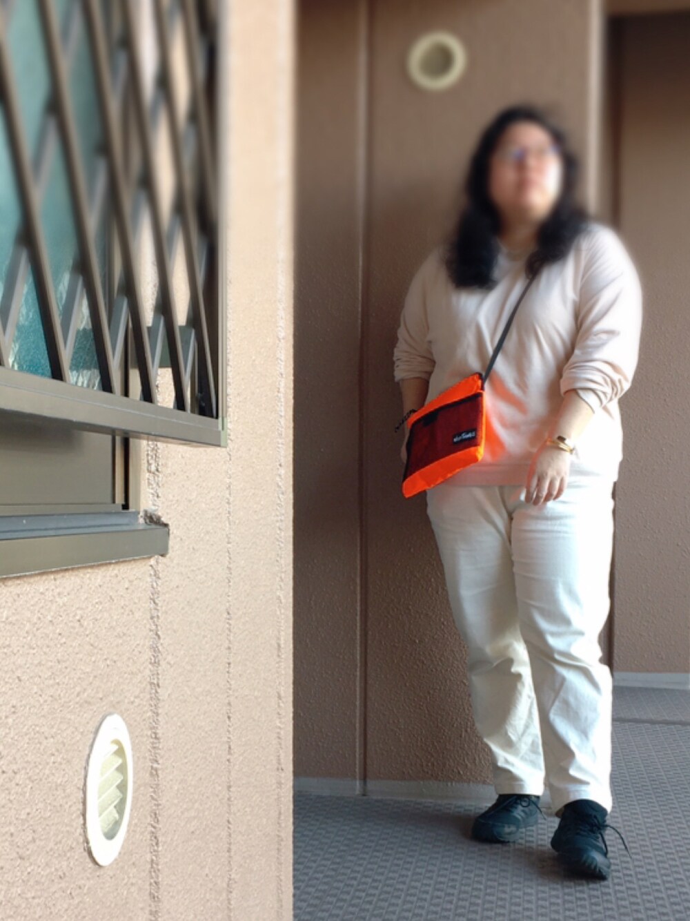 オレンジ系のショルダーバッグ、ベージュ系のスウェット、ホワイト系のパンツを着用したレディースの春コーディネートの1枚目の写真