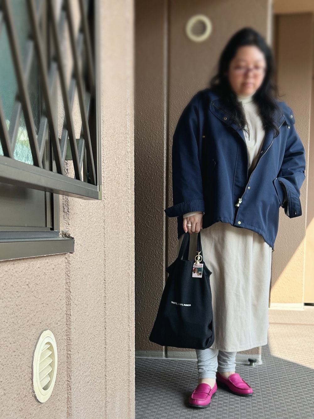 ベージュ系のジャンパースカート、ホワイト系のニット/セーター、ブルー系のマウンテンパーカーを着用したレディースの夏コーディネートの1枚目の写真