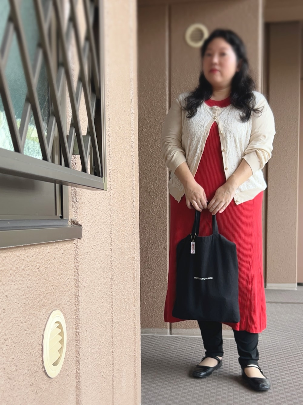 レッド系のワンピース、ベージュ系のカーディガン/ボレロ、ブラック系のトートバッグを着用したレディースの秋コーディネートの1枚目の写真