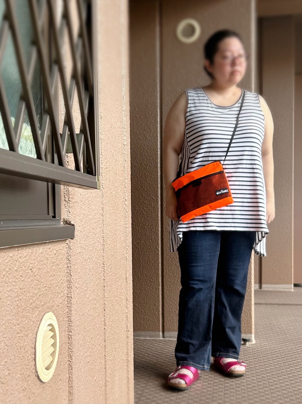 ホワイト系のタンクトップ、オレンジ系のショルダーバッグ、ブルー系のデニムパンツを着用したレディースの夏コーディネートの1枚目の写真