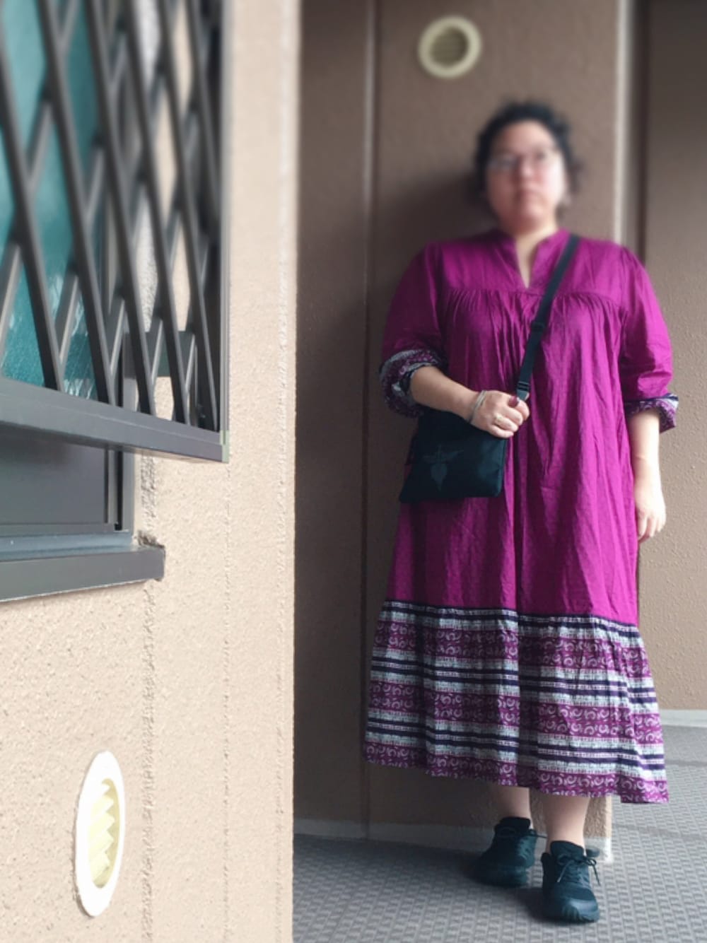 ピンク系のワンピース、ブラック系のショルダーバッグ、ブラック系のスニーカーを着用したレディースの秋コーディネートの1枚目の写真