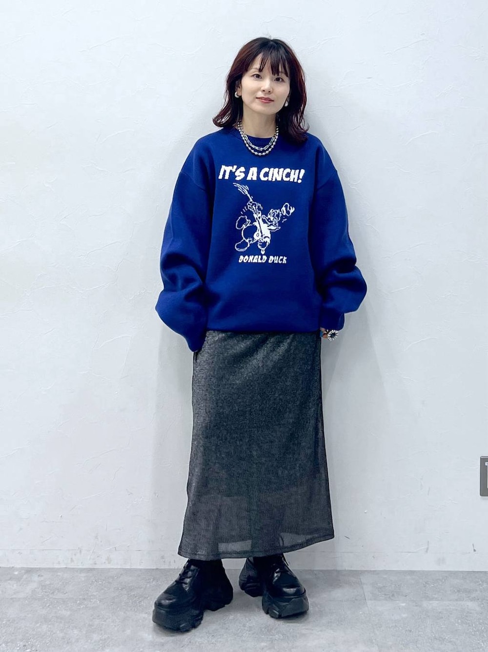 ブラック系のブーツ、ブラック系のスカート、ブルー系のニット/セーターを着用したレディースの冬コーディネートの1枚目の写真