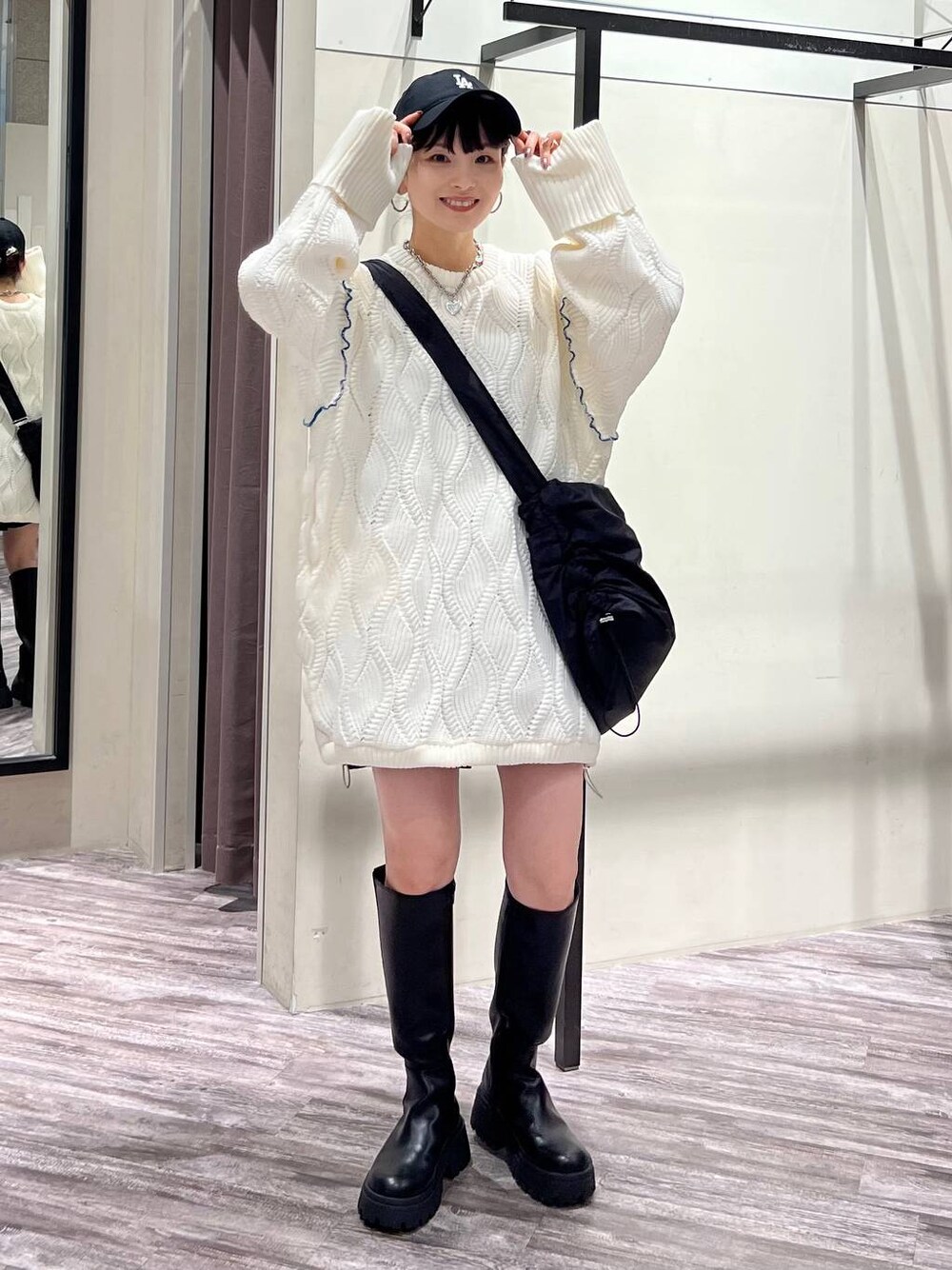 ブラック系のブーツ、ブラック系のショルダーバッグ、ホワイト系のニット/セーターを着用したレディースの冬コーディネートの1枚目の写真