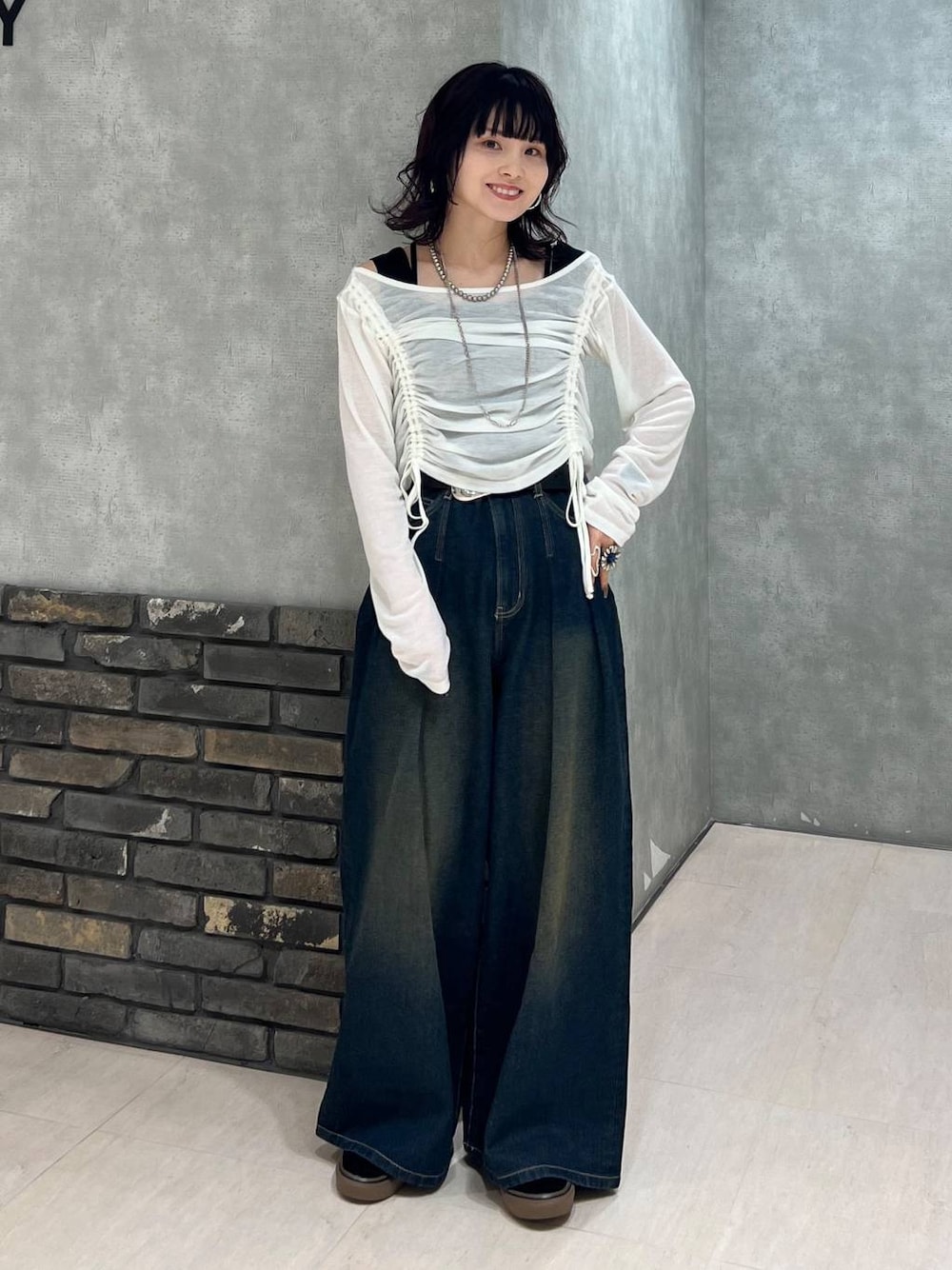 ブルー系のデニムパンツ、ブラック系のタンクトップ、ホワイト系のTシャツ/カットソーを着用したレディースの春コーディネートの1枚目の写真