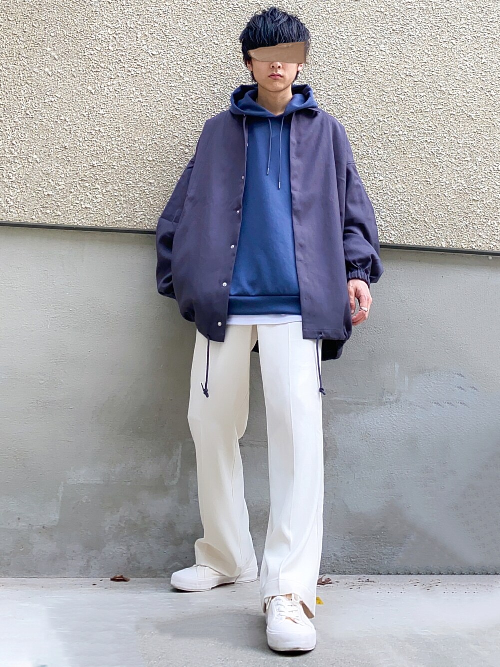 グレー系のブルゾン、ブルー系のトップス、ホワイト系のタンクトップを着用したメンズの秋コーディネートの1枚目の写真