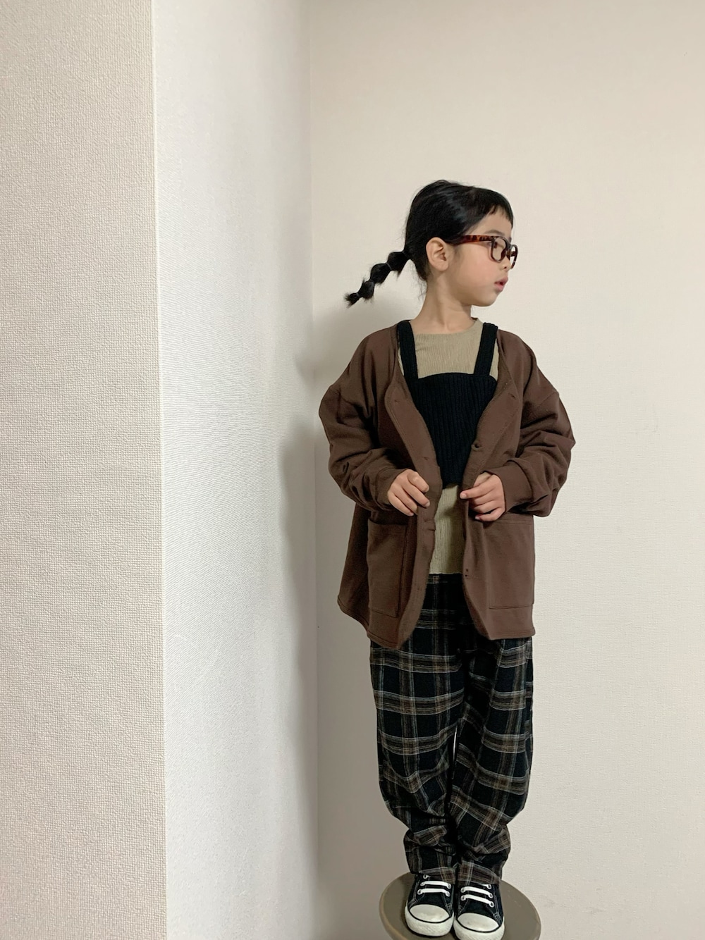 ブラック系のパンツ、ブラウン系のカーディガン/ボレロ、ブラック系のトップスを着用したキッズの冬コーディネートの1枚目の写真