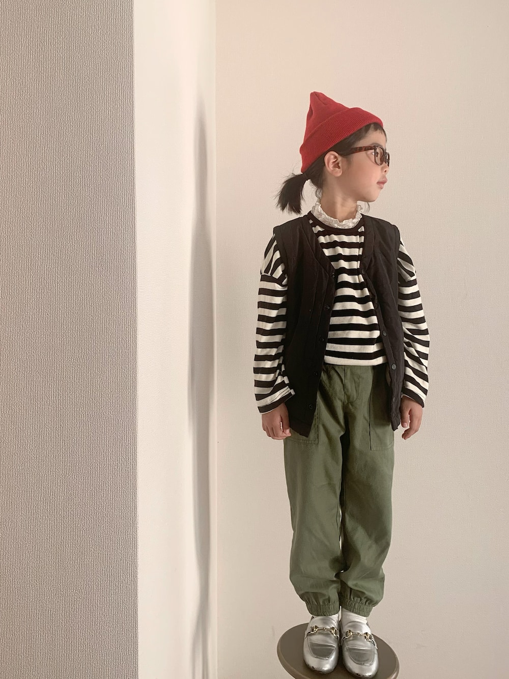 グリーン系のパンツ、シルバー系のローファー、ホワイト系のトップスを着用したキッズの秋コーディネートの1枚目の写真