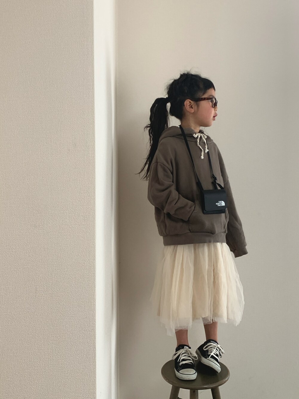 ブラウン系のパーカー、ベージュ系のワンピース/ドレス、ブラック系のスニーカーを着用したキッズの冬コーディネートの1枚目の写真