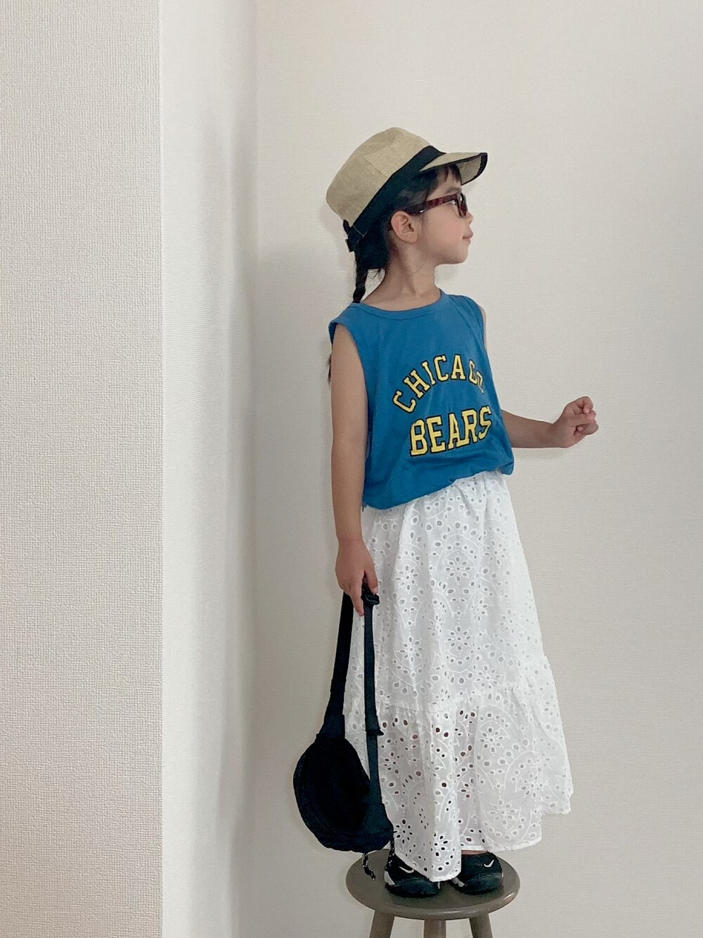 ホワイト系のスカート、ブラック系のボディバッグ/ウエストポーチ、ブラック系のスニーカーを着用したキッズの夏コーディネートの1枚目の写真