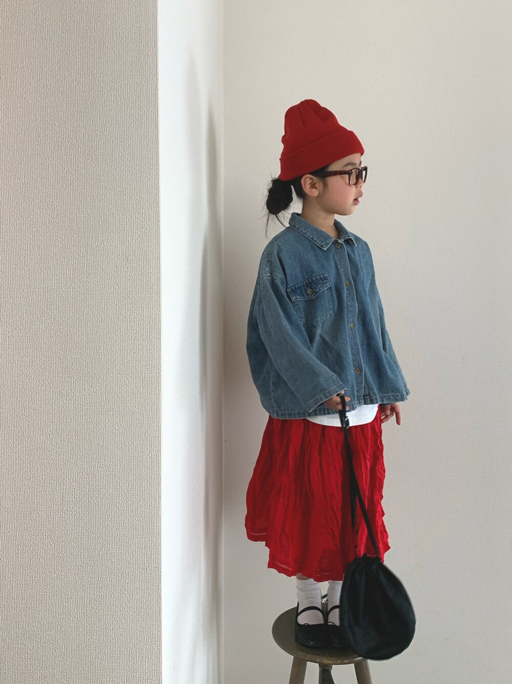 ブラック系のバッグ、ブラック系のバレエシューズ、レッド系のスカートを着用したキッズの冬コーディネートの1枚目の写真