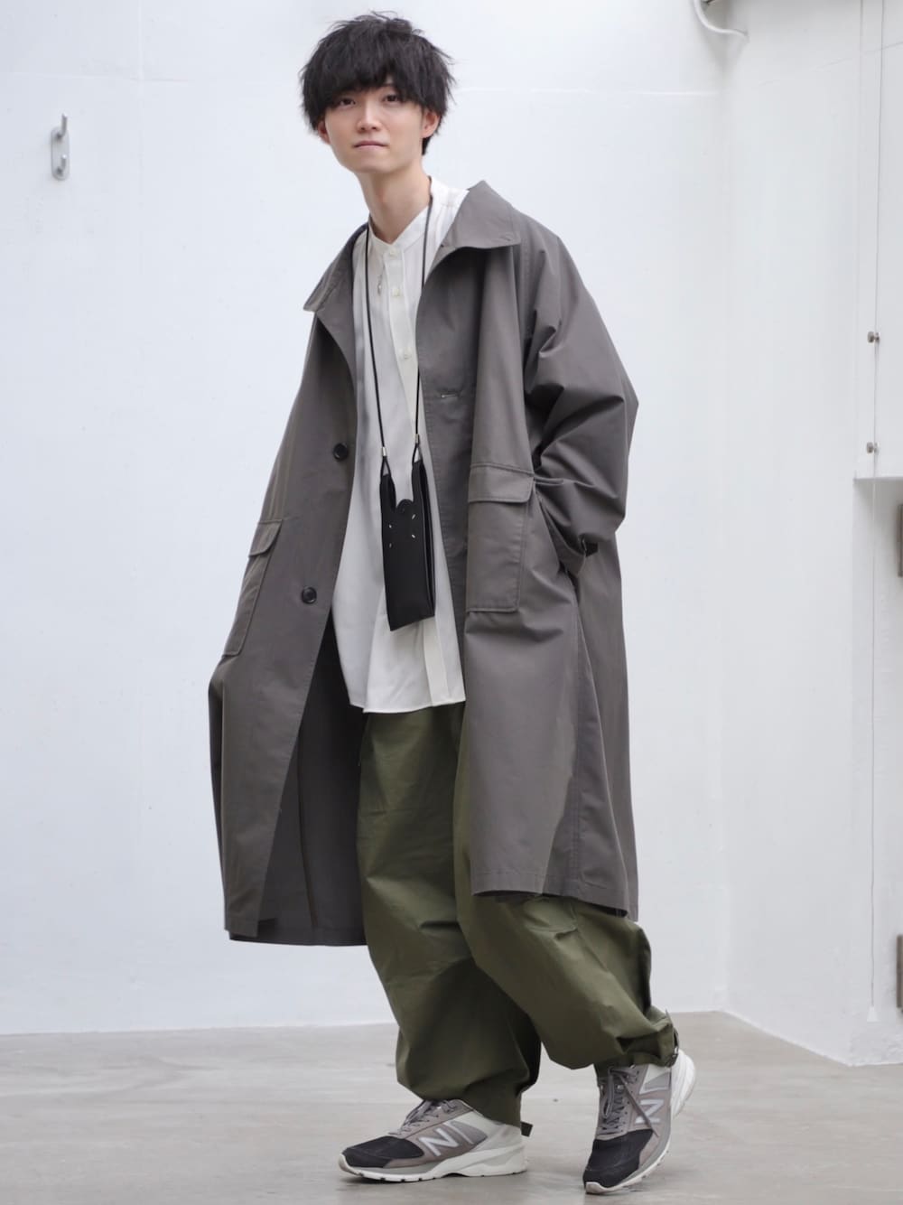 グレー系のトレンチコート、ホワイト系のシャツ/ブラウス、ブラック系のショルダーバッグを着用したメンズの春コーディネートの1枚目の写真