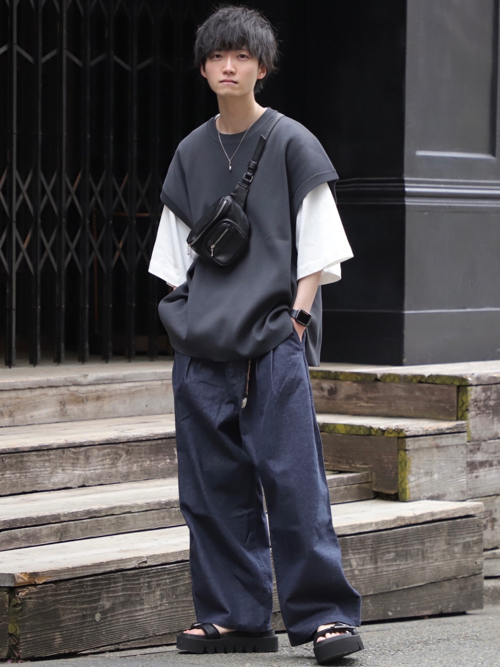 グレー系のベスト、ブラック系のボディバッグ/ウエストポーチ、ブルー系のスラックスを着用したメンズの春コーディネートの1枚目の写真