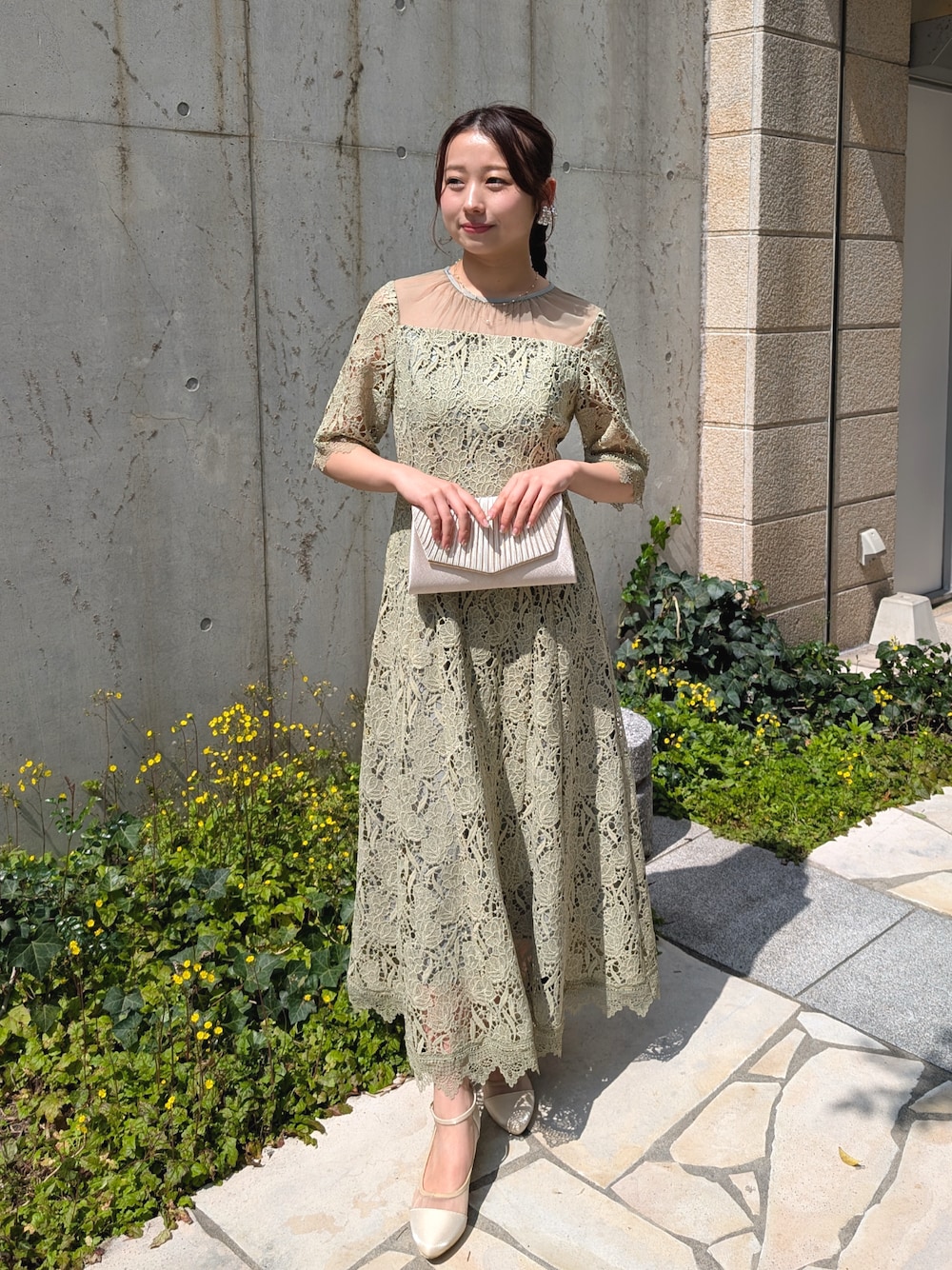グリーン系のドレス、ベージュ系のパンプス、ベージュ系のクラッチバッグを着用したレディースの春コーディネートの1枚目の写真