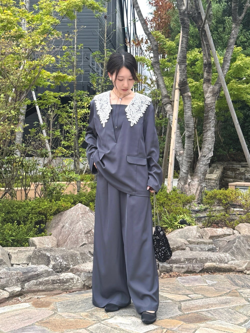 ブルー系のパンツドレス、ブラック系のハンドバッグを着用したレディースの秋コーディネートの1枚目の写真