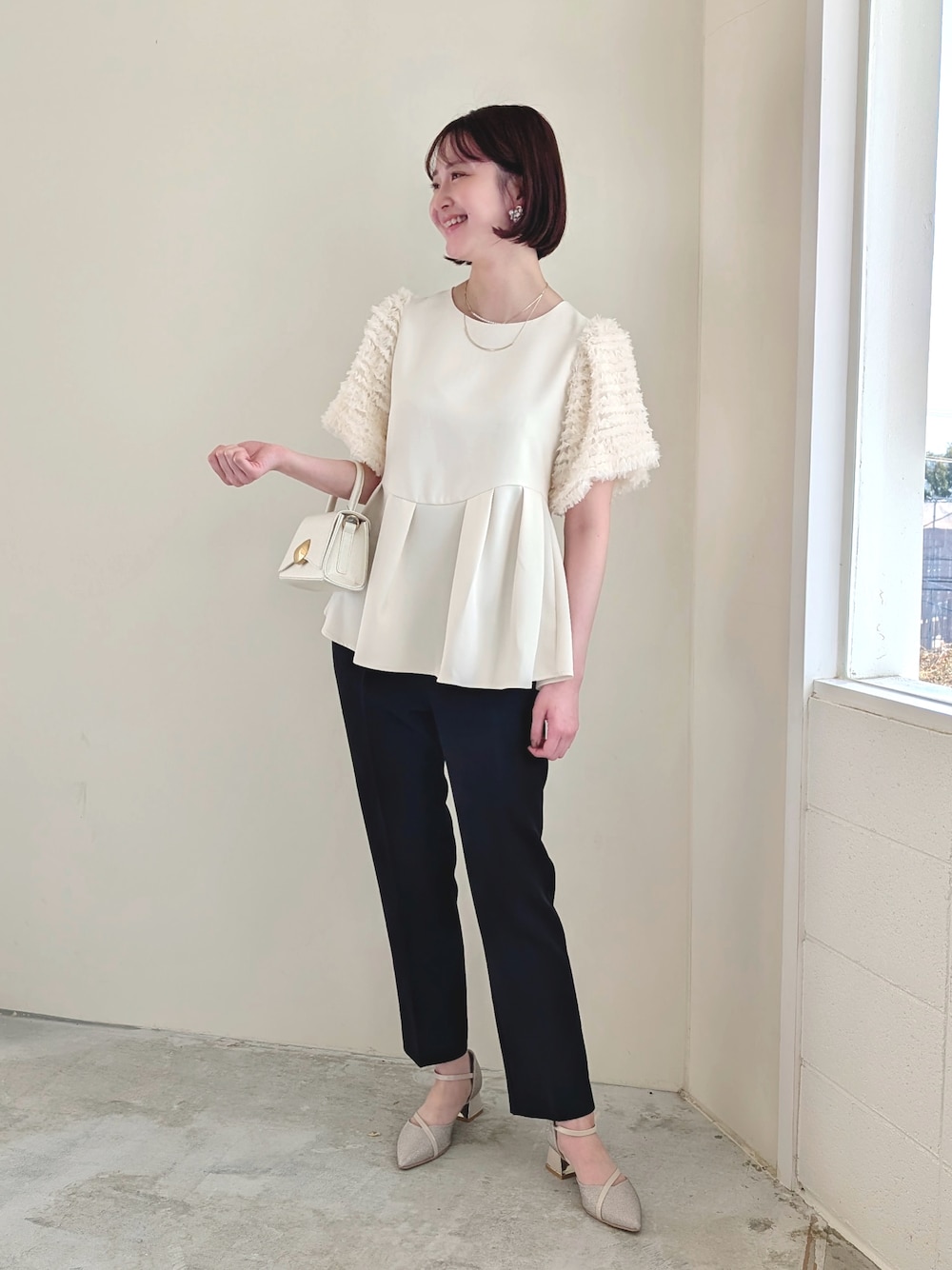 ホワイト系のパンツドレス、ホワイト系のハンドバッグ、ベージュ系のドレスシューズを着用したレディースの冬コーディネートの1枚目の写真